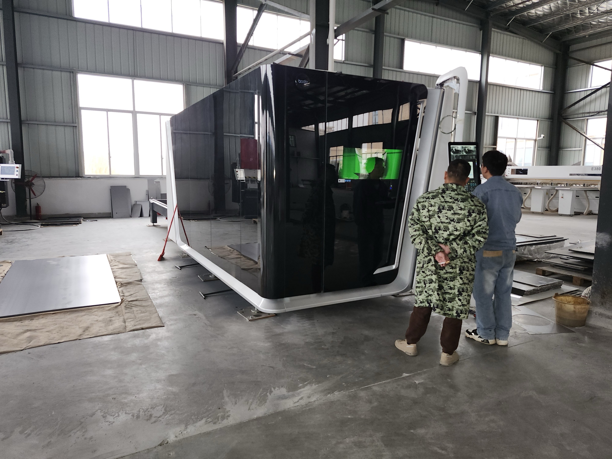 Enclosed sheet-metal cutting equipment with two team members at the control screen