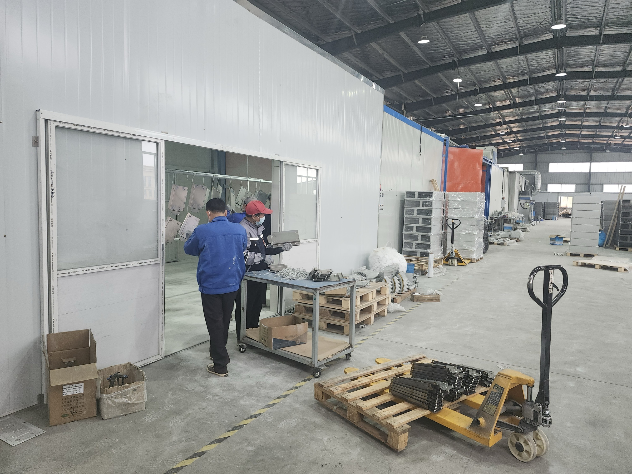 Two team members checking a component near an enclosed workshop area