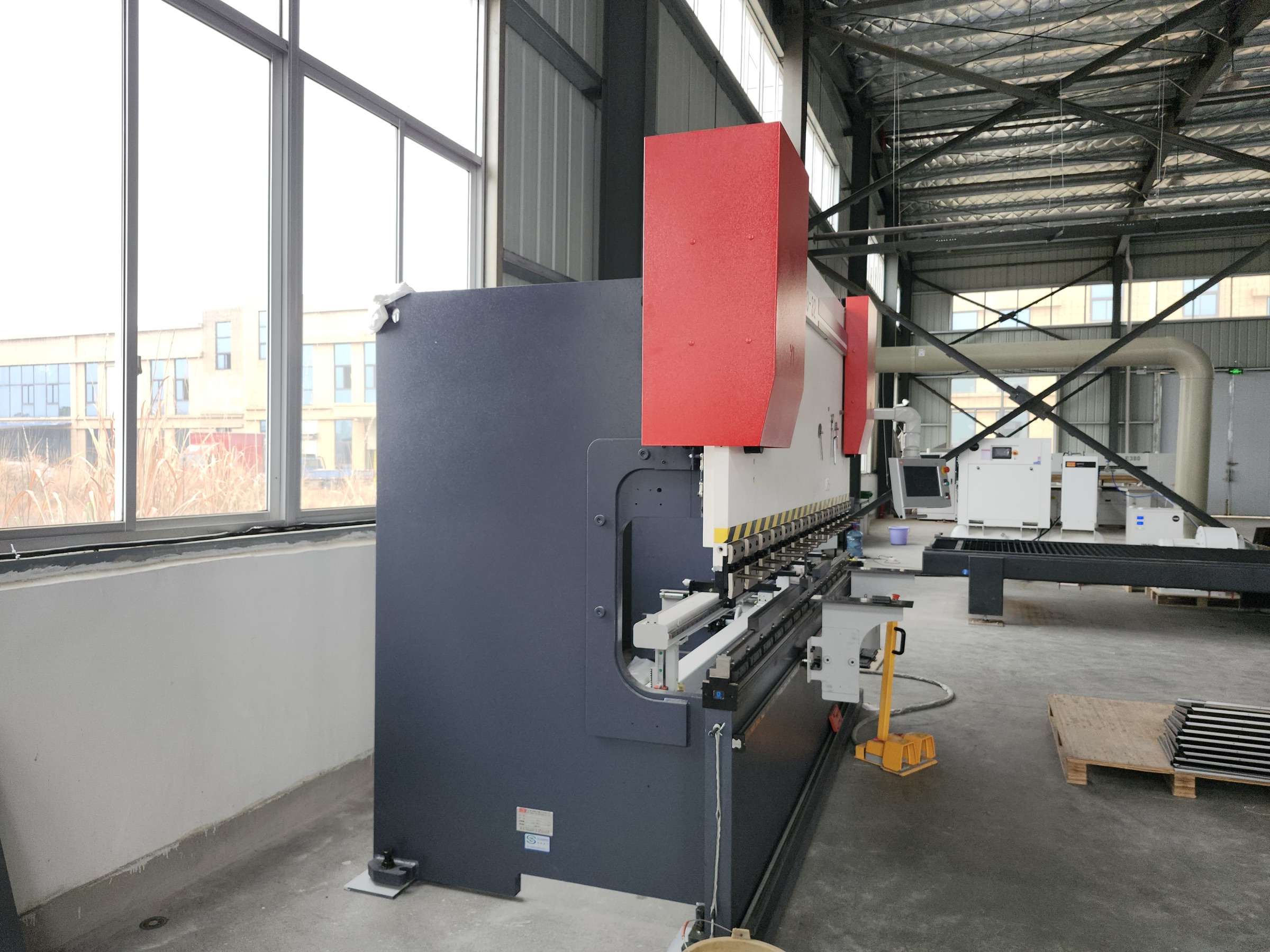 Large sheet-forming machine positioned beside the workshop windows