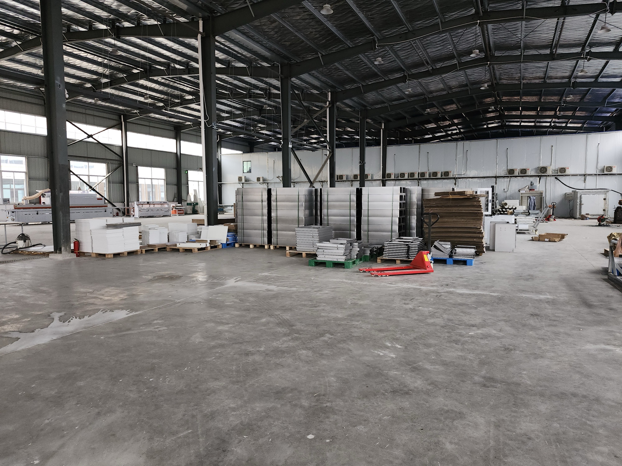 Workshop floor with stacked metal and panel components on pallets