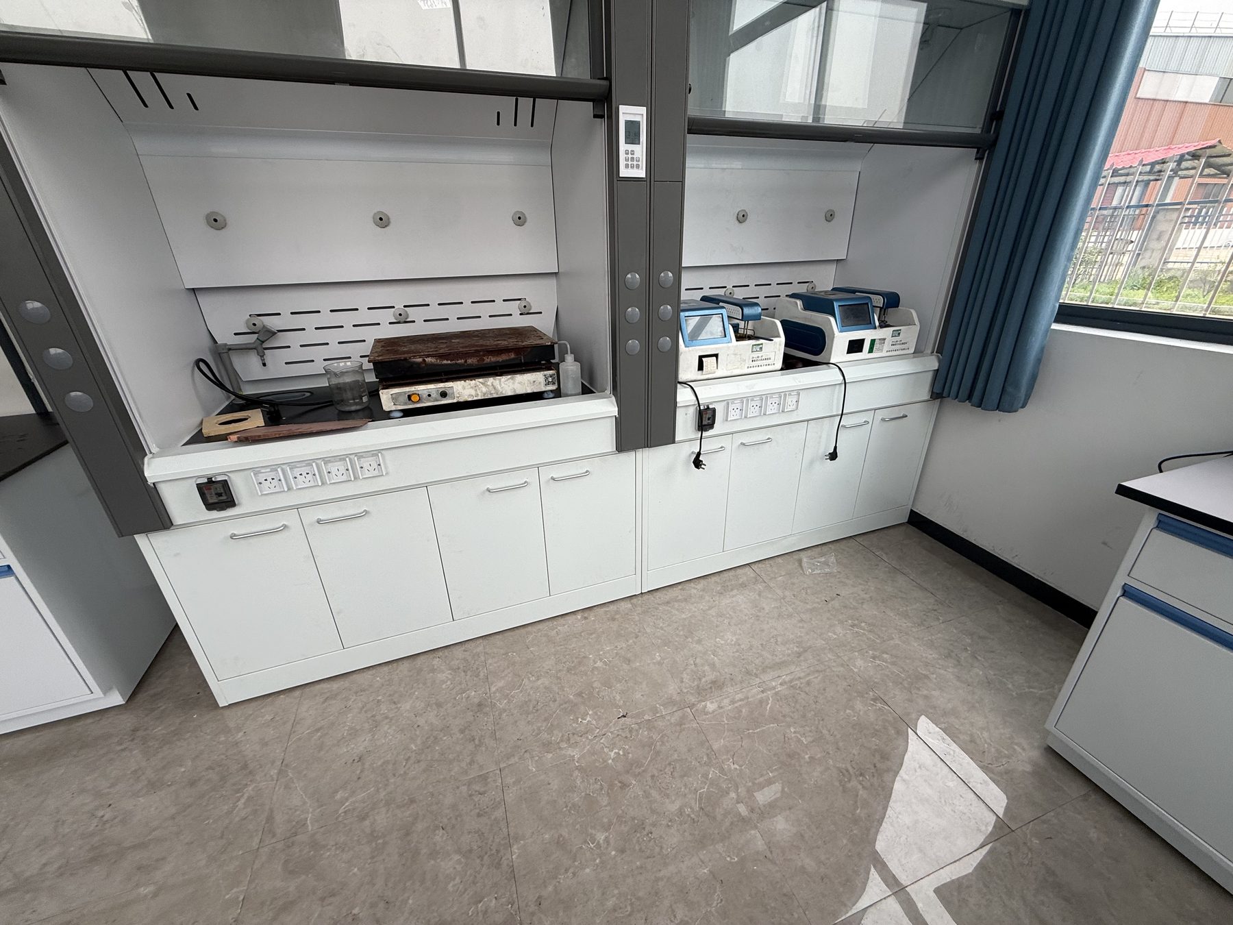 Laboratory fume hood installed above base storage and an adjacent service bench