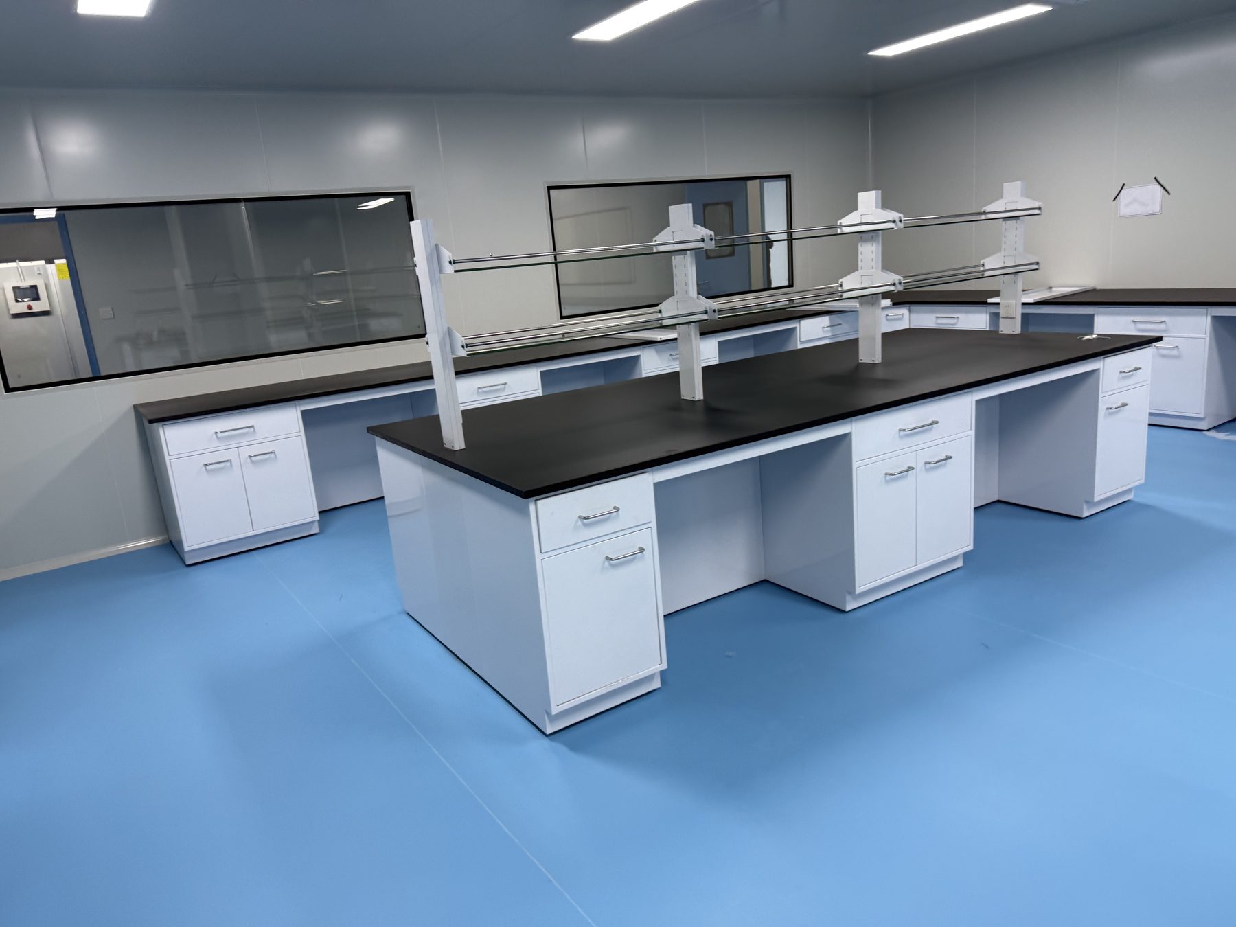 Laboratory island bench with black worktop, sink, service fixtures, and under-bench storage
