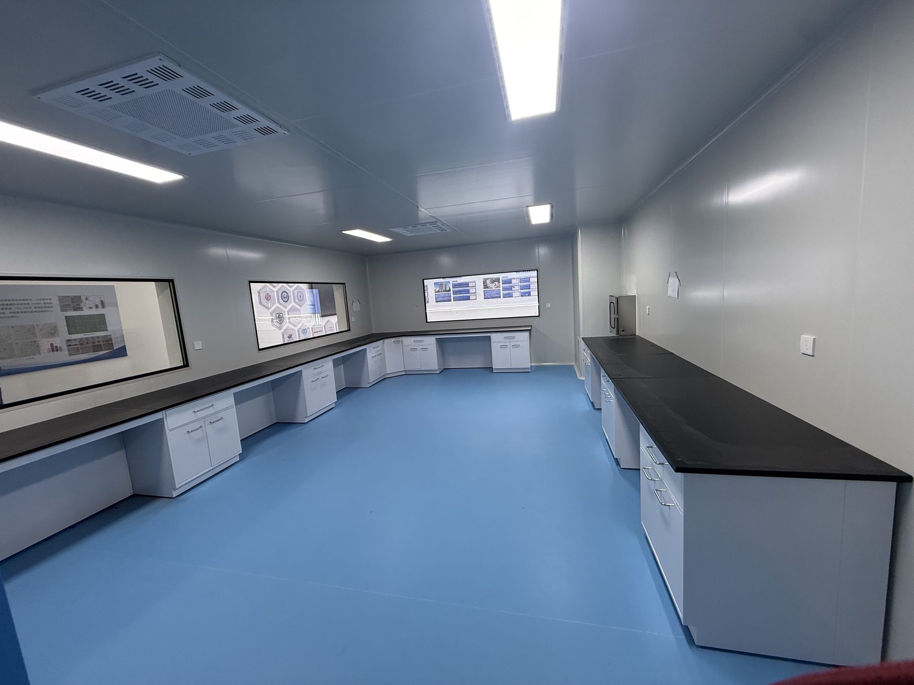 Clean laboratory with long black wall worktops and white under-bench cabinets
