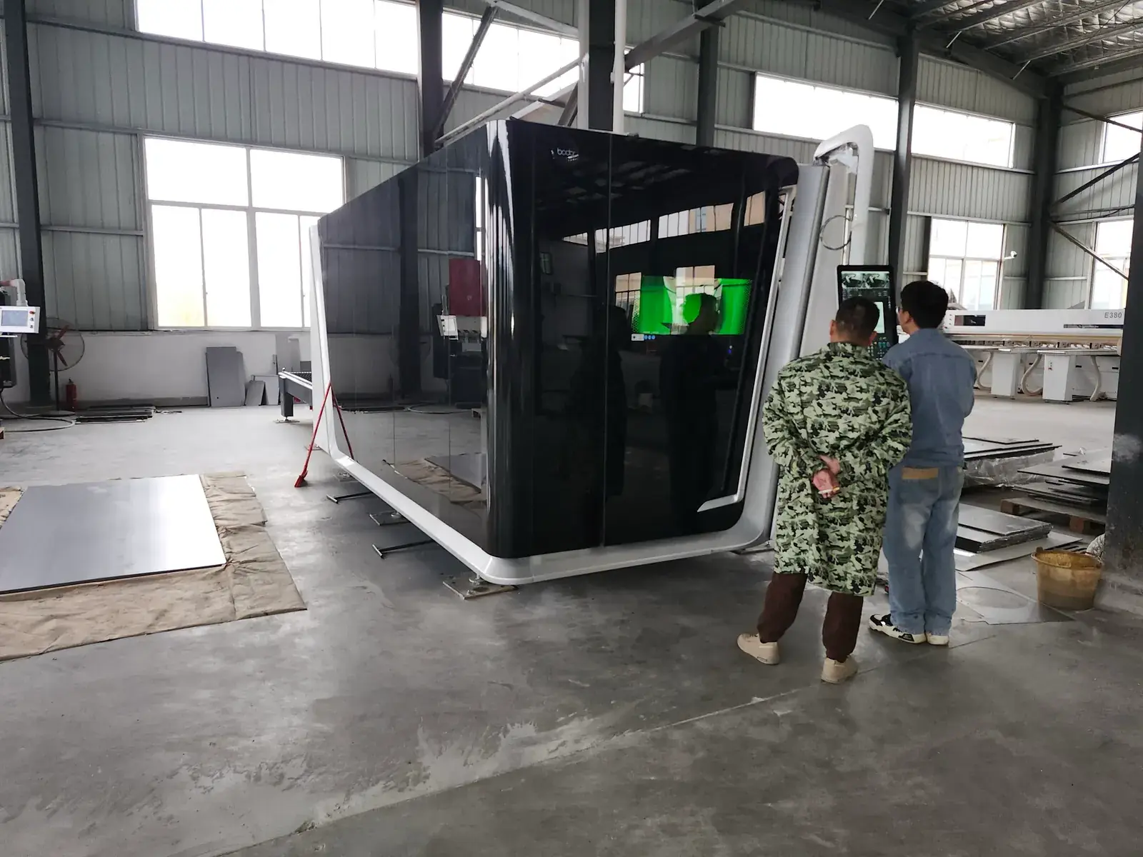 Enclosed sheet-metal cutting equipment with two team members at the control screen