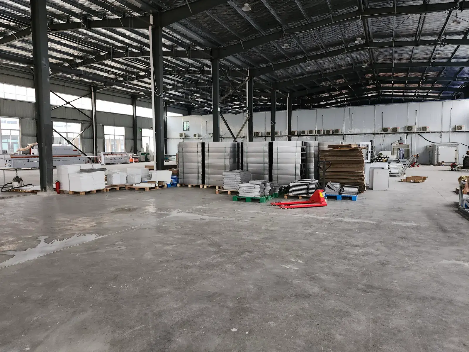 Workshop floor with stacked metal and panel components on pallets